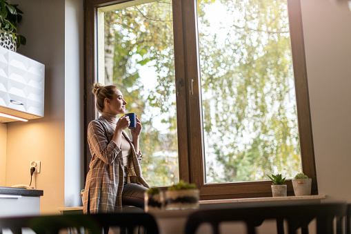 Smiling businesswoman with cup of coffee looking out of window