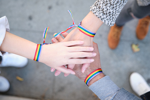 Manos de un grupo de tres personas con pulseras de bandera LGBT photo