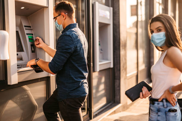 istock Man with face mask withdrawing money at ATM 1280385487