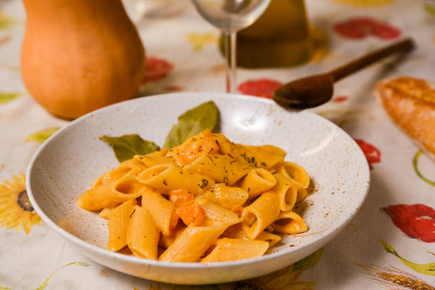 butternut squash pasta with creamy , fresh pumpkin sauce on white plate and colorful table cloth. Traditional italian autumn pasta stock photo