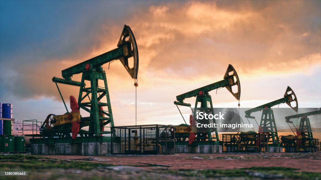 Working Pumpjacks On Sunset Working oil pumps against a sunset sky. Crude Oil Stock Photo
