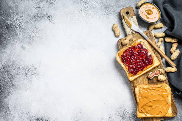 Peanut butter and jelly on white bread toasts.  White background. Top view. Copy space Peanut butter and jelly on white bread toasts.  White background. Top view. Copy space. peanut butter and jelly sandwich stock pictures, royalty-free photos & images