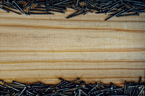 Small nails are scattered on the wooden Board. Background with space to copy. Advertising nails on wood