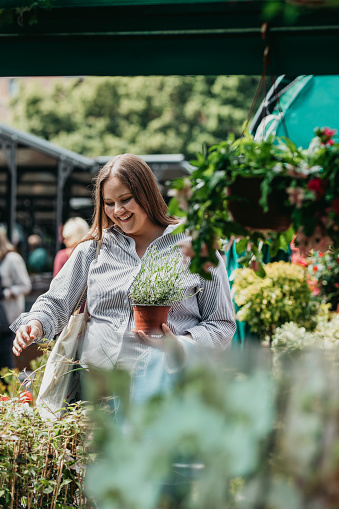Woman buying potted flowers and herbs at a local open market.