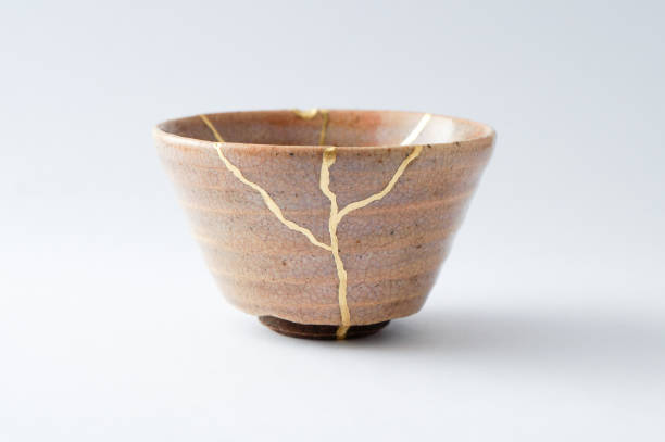 Antique broken Japanese cup repaired with gold kintsugi technique stock photo