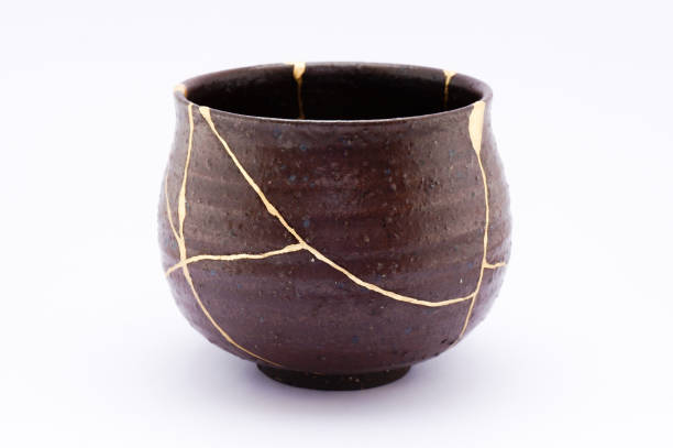 Antique broken Japanese black bowl repaired with gold kintsugi technique stock photo