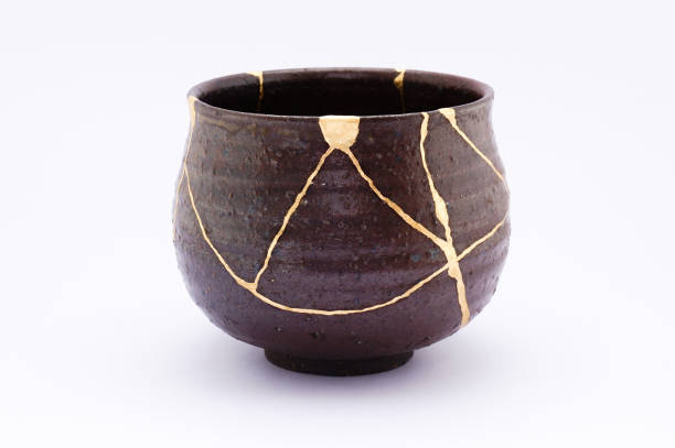 Antique broken Japanese black bowl repaired with gold kintsugi technique stock photo