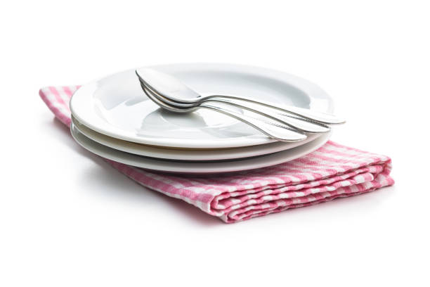 Dessert plates and spoons on checkered napkin isolated on white background.