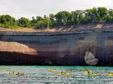 Pictured Rocks National Lakeshore on Lake Superior in Munising, Michigan - Upper Peninsula - They get their colors from mineral stains. Best way to see them is by boat or kayak. There are groups of people kayaking.