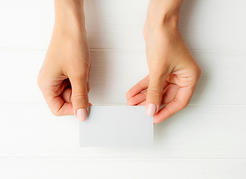 Woman holding white business card in hands. Tamplate for your design.