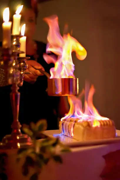 Flambé of a dessert during a party with large flames on the omelet and in the pan