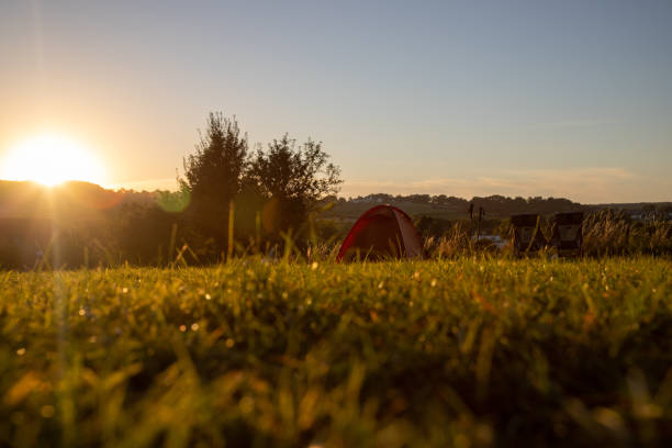 istock Tent and chairs on a hill in grassland with the sun setting 1280396474