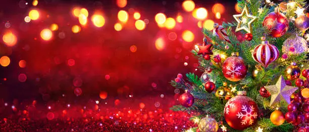 Photo of Abstract Christmas Tree With Baubles And Bokeh Lights On Red Glitter Background