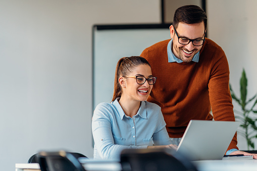 Young businessman helping his female colleague in office to finish business report