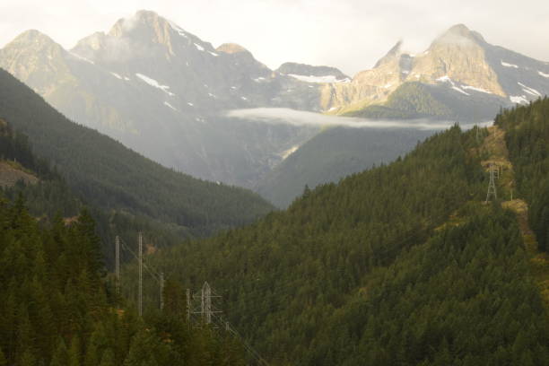 istock Power Lines Switching Across Forested Mountain Ridge With Large Mountain Peak In The Background 1280398636