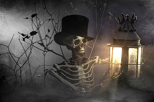 Studio shot of a skeleton in a misty forest carrying a lamp, Halloween