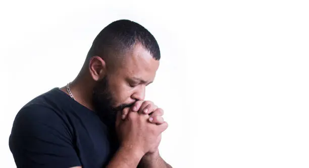 man with faith and fear during pandemic praying with crossed hands on white background