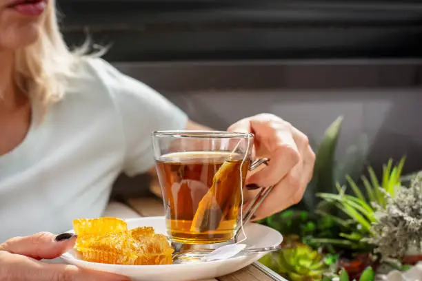 Woman enjoying on a terrace while drinking camomile tea with honey