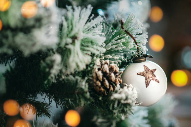 White Christmas ornament. Close up Beautiful white Christmas ornament on pine tree. This year, family decided to have Christmas tree in white so they got fake snow, pine cones, lights, and Christmas balls to mach. fake snow stock pictures, royalty-free photos & images