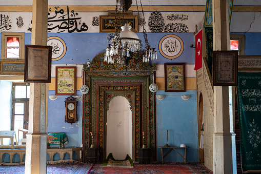 Altar in antique mosque of Sarihacilar village near Akseki, Antalya, Turkey. The altar has wooden ornaments in Ottoman style. Arabic text on wall read Mohammed and Allah. No people are seen in frame. Shot with a full frame mirrorless camera.