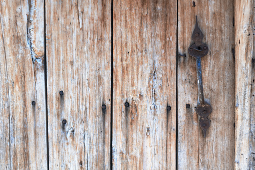 Grunge wooden door background with metal nails and doorknob. No people are seen in frame. Shot with a full frame mirrorless camera.