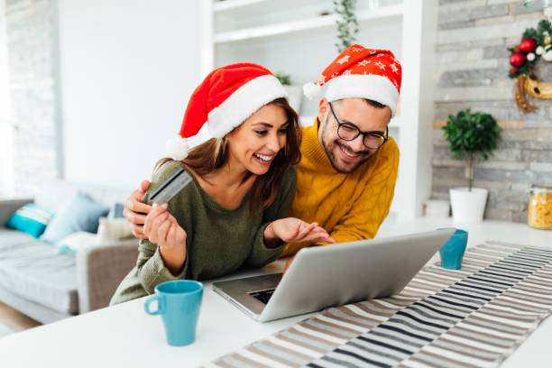 feliz pareja caucásica comprando en línea casa durante las vacaciones de invierno - holiday shopping fotografías e imágenes de stock