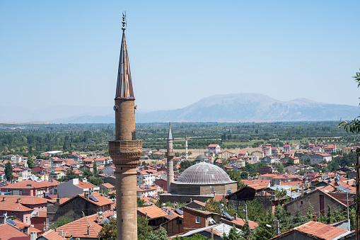 General view of town of Senirket near Isparta, Turkey. Minarets and mosque domes are seen in townscape. Sky is blue and clear. No people are seen in frame. Shot with a full frame mirrorless camera.