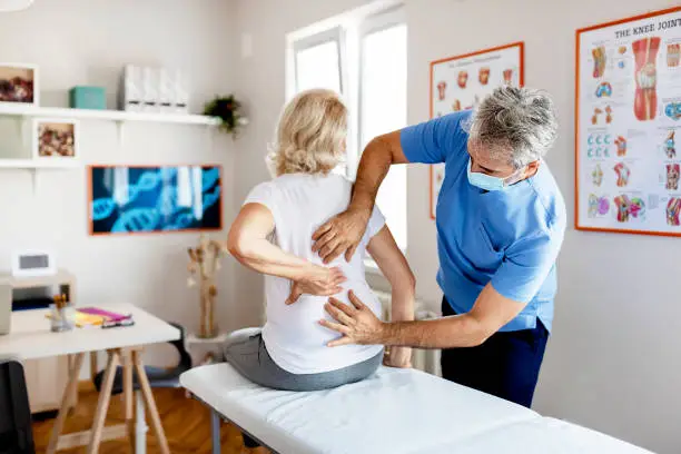 Modern Rehabilitation Physiotherapy Worker With Senior Client in Clinic. Pain Relief Concept. Physiotherapy, Injury Rehabilitation
