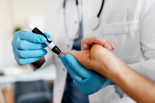 Doctor making diabetes blood test on senior woman, close up