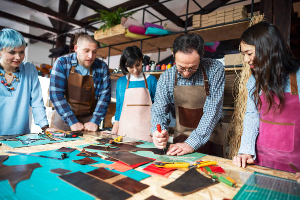 istock Senior craftsman cutting the leather while everyone is looking 1280422473