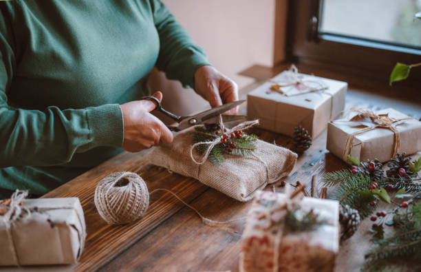 Woman decorating Christmas gifts. Unrecognizable woman decorating Christmas gift without plastic, zero waste organic materials. christmas human hand christmas ornament decoration stock pictures, royalty-free photos & images