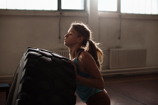 Young fit woman flipping a truck tyre during a workout