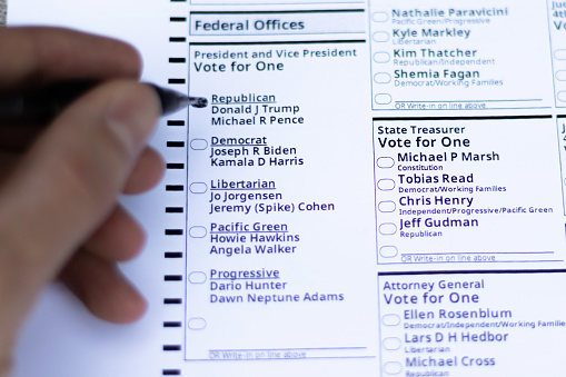 White person with pen in hand voting for republican presidential candidate Donald Trump during early vote by mail in the state of Oregon. Portland, Oregon / USA - October 2020.