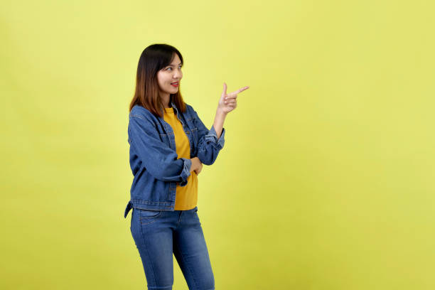 istock Young Asian woman pointing hands on yellow background 1280434461