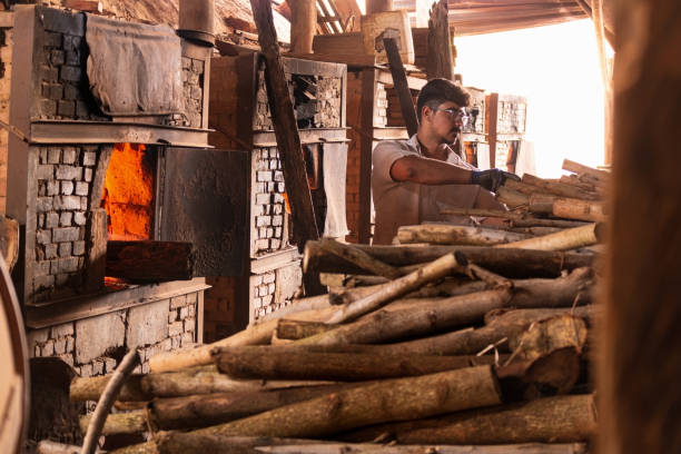 istock Young man putting firewood on industrial oven. Brick yard. 1280441488