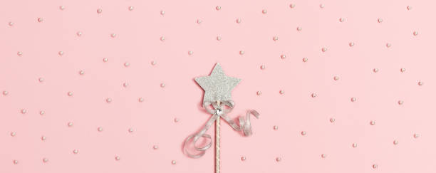 istock Festive decoration, magic wand, bright silver star with shine on soft pink background with white beads. Minimal holiday concept. Banner for website. 1280450295