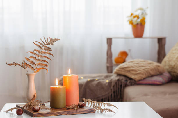 brennende kerzen mit herbst-dekor auf weißem tisch zu hause - herbst kerzen stock-fotos und bilder