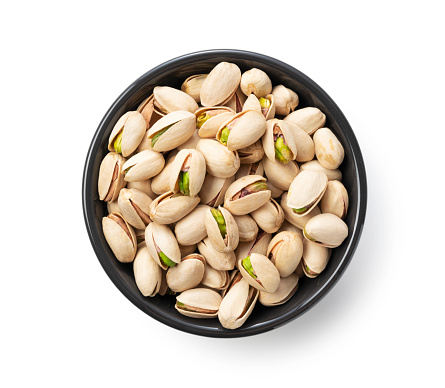 A bird's-eye view of the pistachios in a bowl set against a white background