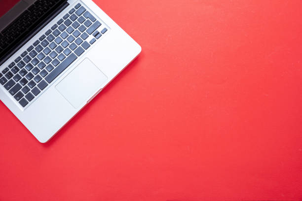 istock Computer on red color background. Open laptop metal silver color top view. 1280453450