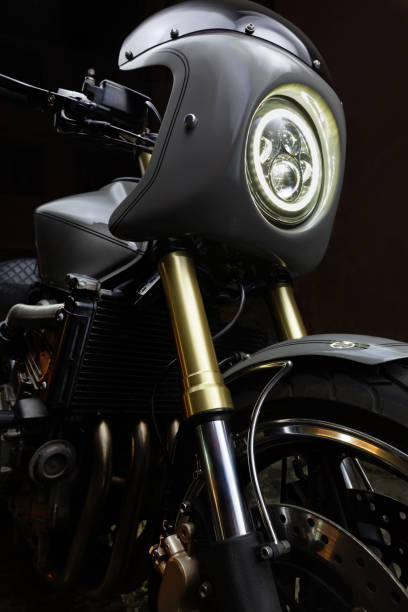 istock Custom caferacer motorbike on dark background with its headlight on. 1280454905