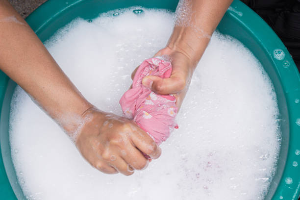 Female hands wash clothing by hand with detergent in basin. selective focus and space for text.