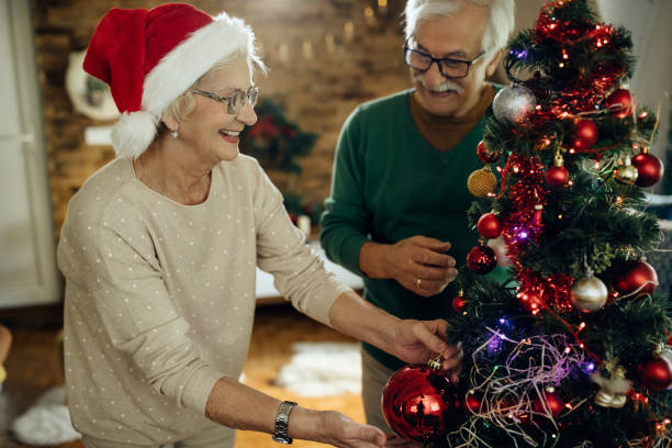 istock Happy senior couple having fun while decorating Christmas tree at home. 1280457035