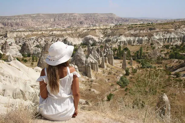 Back View Young  Woman Sitting and watching mushroom shaped fairy chimney  in Cappadocia,Turkey .Concept of travel and adventure