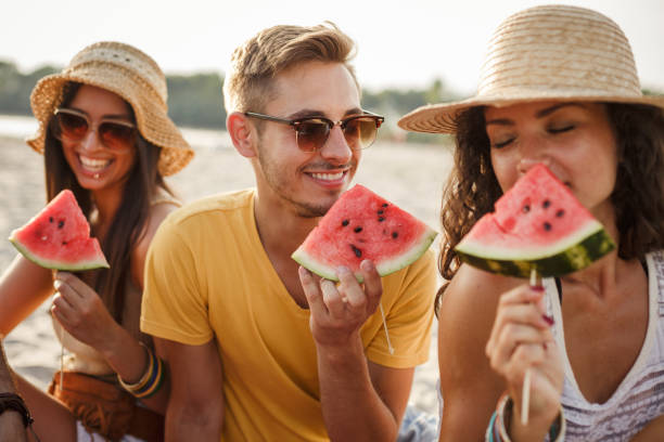 istock Friends enjoying fresh watermelon on a beach picnic 1280459319
