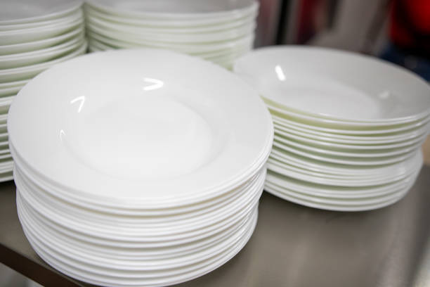 istock Stacks of many white plates on a wire rack shelf in a commercial kitchen 1280459521
