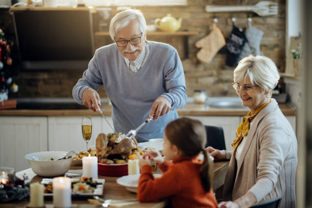istock Happy mature man carving roasted Thanksgiving turkey at dining table. 1280459755
