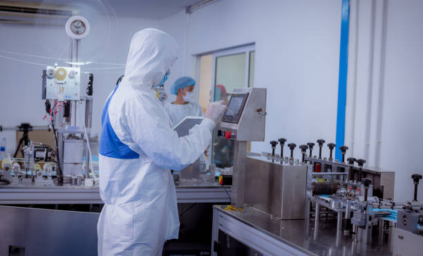 istock Technician worker wearing protective suite , glove are inspect machine with check  face mask manufacturing process to safe and against from virus 1280459943