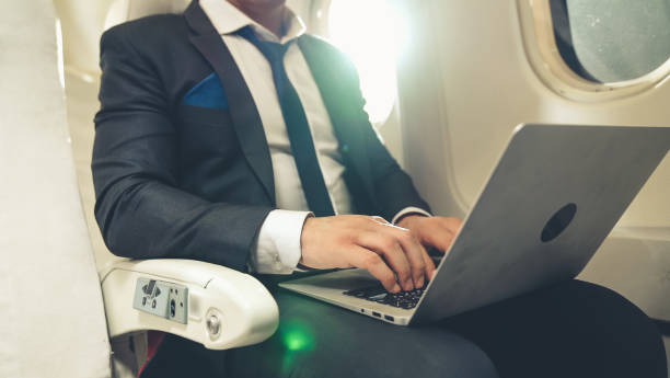 istock Young businessman using laptop computer in airplane 1280464476