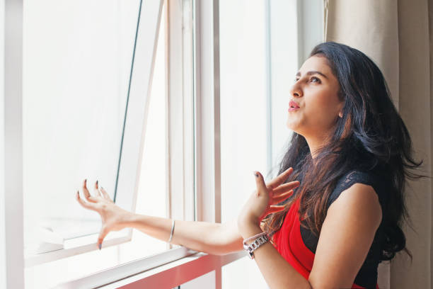 Hot weather in India Young Indian woman in saree opening window because of extreme summer heat unpleasant smell stock pictures, royalty-free photos & images