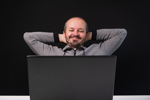 Businessman writing note in notepad with computer while working in office.